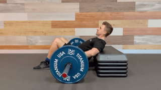 Barbell hip thrust demonstration filmed on a clean branded gym backdrop