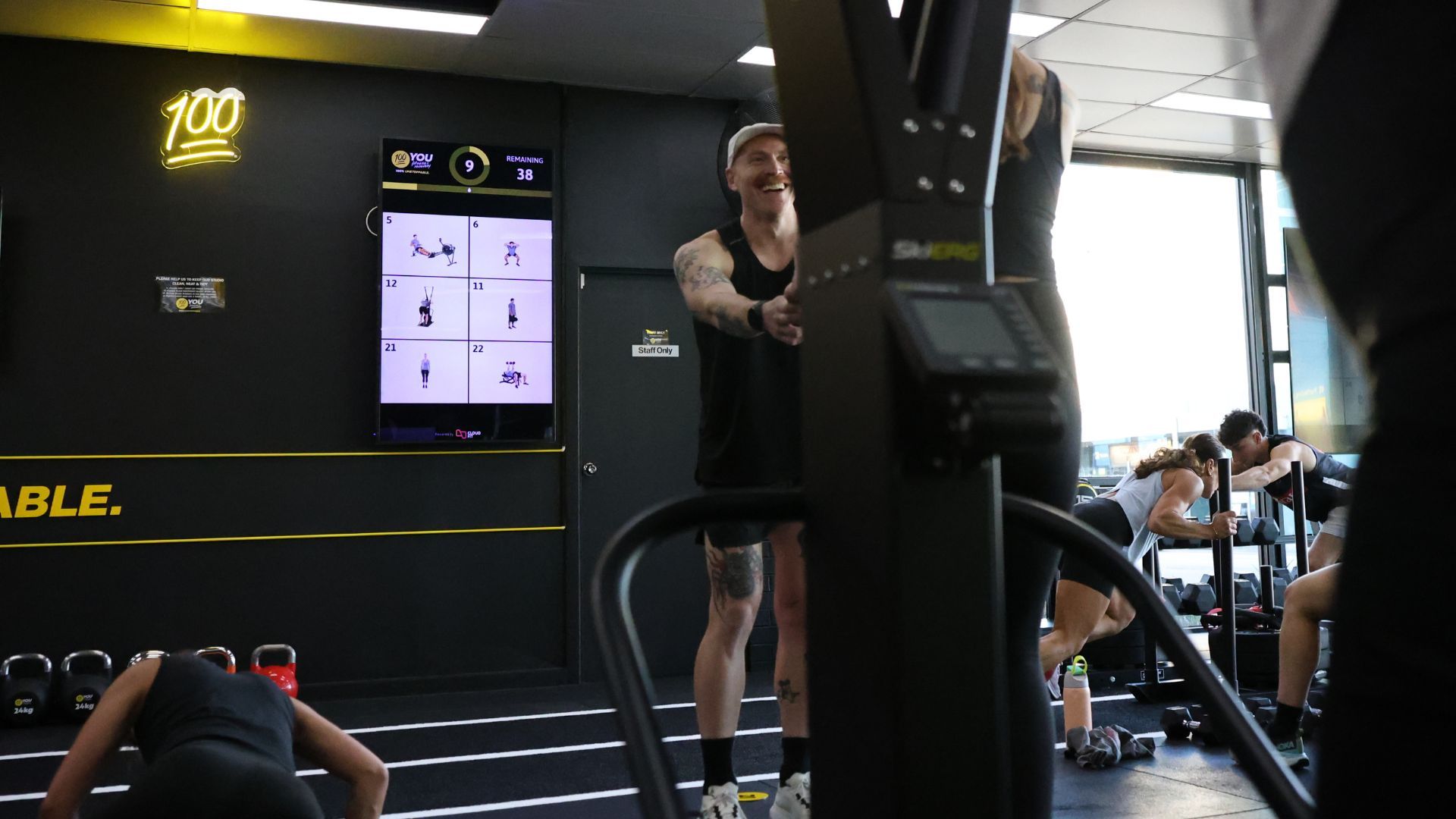 Coach leading a HIIT class with CloudFit on screen
