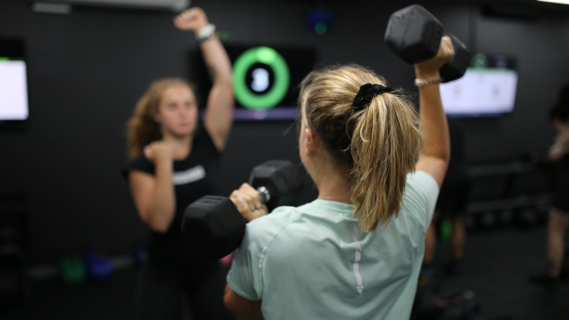 Coach leading a strength class with CloudFit on screen